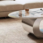 Table basse ovale de 124 cm avec plateau en pierre frittée imitation marbre et piètement sculptural en acier inoxydable