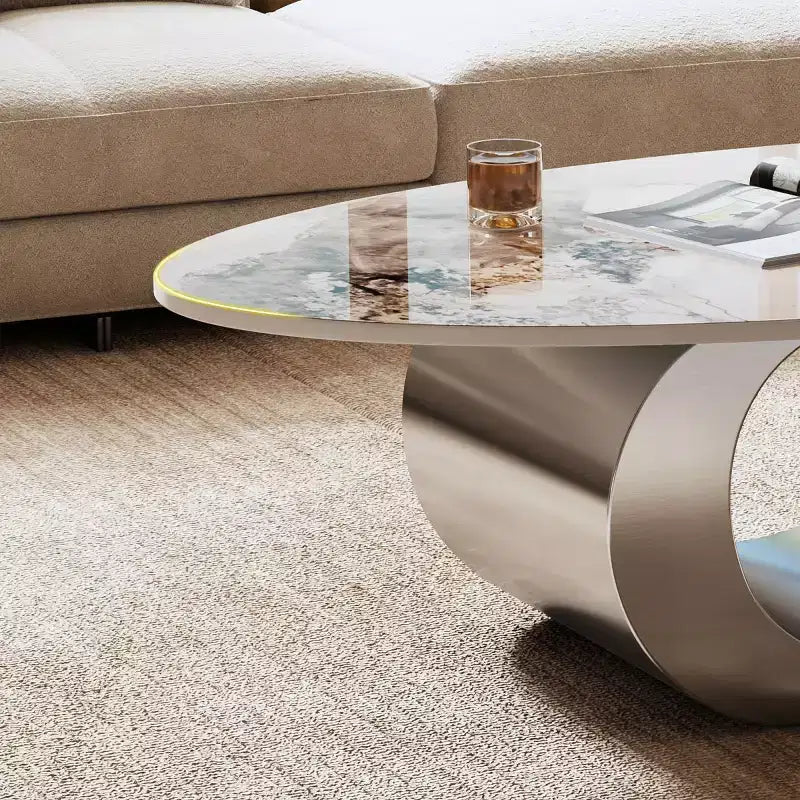 Table basse ovale de 124 cm avec plateau en pierre frittée imitation marbre et piètement sculptural en acier inoxydable